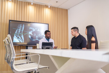 A doctor working with tablet computer to explain progressive of disease to patient and family in...