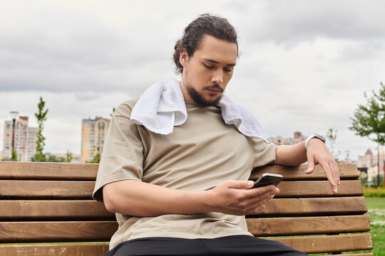 Sporty young man taking a break outdoors while checking his phone