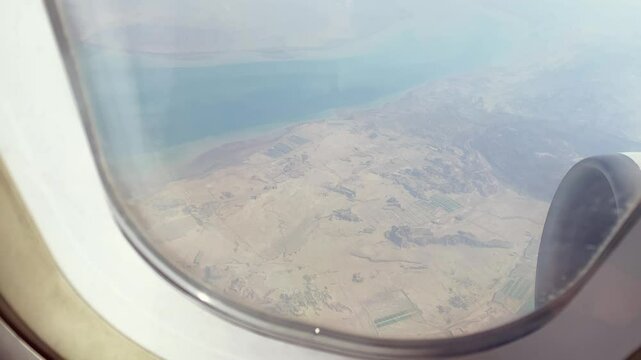 Qeshm Island from airplane window passengers POV. Dramatic island terrain, coastline, and desert beauty in the Persian Gulf during flight over southern Iran. Travel destination in middle east