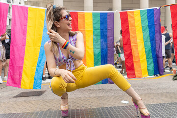 Young woman crouching with rainbow and pansexual flags at gay pride parade