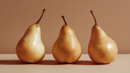 Three ripe yellow pears are arranged in a row against a soft beige background