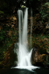 Obraz premium Veliki Buk waterfall in Lisine reserve, Serbia, with a strong vertical flow cascading over mossy cliffs into a clear pool below. Captured with a soft long exposure effect.