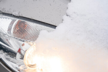 Close-up of removing snow and ice from headlighst before driving concept