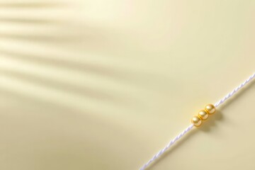Elegant golden pearls on subtle beige background and white thread