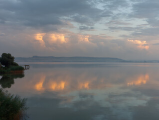 Serene lake sunrise with cloudy sky reflection