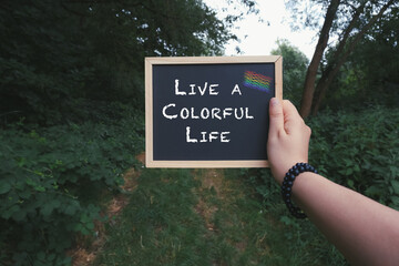 Person holding a chalkboard with the words Live a colorful life