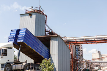 Unloading Grain at Elevator Facility with Raised Truck Bed and Modern Silos in Agricultural Logistics Industry © st.kolesnikov