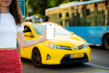 Close-Up of Woman Holding Smartphone with Blank Screen Near Taxi and Bus