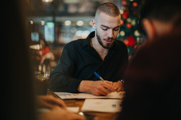 A professional focused on taking notes while engaged in a collaborative work session, with a warm...