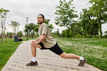 Young man performs outdoor stretches to enhance flexibility and fitness during workout