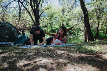A young couple enjoys outdoor camping, relaxing on a blanket, surrounded by nature with a hammock...