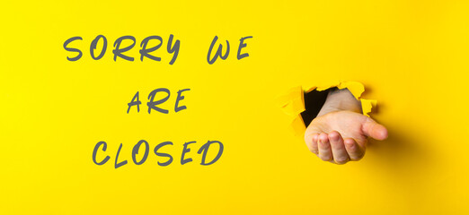 Sorry we are closed sign with a hand holding a hole in it