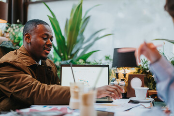 Two business individuals collaborate in a modern cafe setting, engaging in the discussion of...