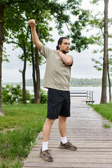 Young sporty man enjoys outdoor workout by the serene lakefront on a cloudy day