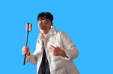 Young Man Holding Selfie Stick and Water Bottle Against Bright Blue Background