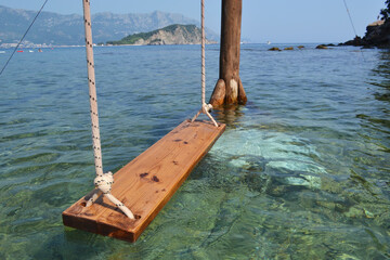 conic Water Swing in the Crystal Clear Sea of Budva, Montenegro, with Rocky Coastline, Green Hills,...