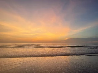 Crédence de cuisine Beige Sunrise at a tropical beach with soft golden tones reflecting on the calm sea. Peaceful and inspiring coastal view.  © Thaila