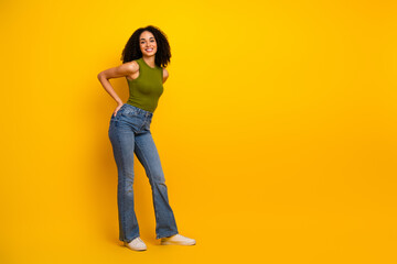 Fototapeta premium Stylish young woman in casual fashion standing confidently on a vibrant yellow background, expressing joy and charm