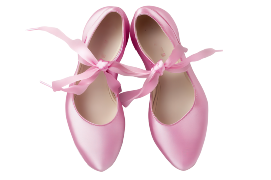 Pink satin ballet shoes with ribbon laces laid out on a neutral background ready for a dance class or rehearsal in a studio setting during early morning hours