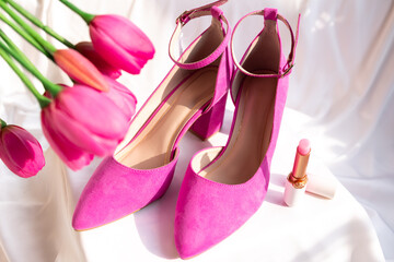 Pink high-heeled shoes with ankle straps on a white surface. Fashion and feminine elegance.