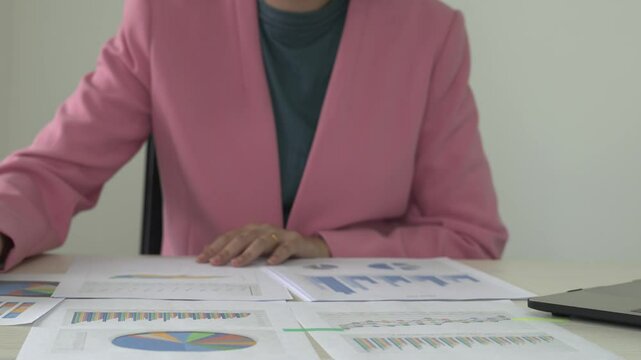 Real estate gent asian woman is reading and checking paper documents, signing the contract to send to her business partner. Concentrated smart ambitious lady is preparing research, remote freelancer.