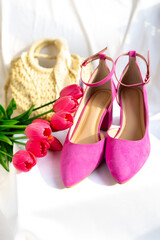 Pink high-heeled shoes with ankle straps on a white surface. Fashion and feminine elegance.