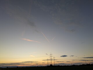 Airplane contrails glowing in warm sunset colors across a dramatic sky, creating dynamic lines of...