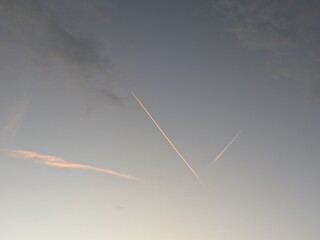 Airplane contrails glowing in warm sunset colors across a dramatic sky, creating dynamic lines of...