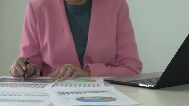 Real estate gent asian woman is reading and checking paper documents, signing the contract to send to her business partner. Concentrated smart ambitious lady is preparing research, remote freelancer.