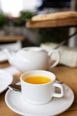 A freshly baked pizza is laid out on a wooden table, as well as a white teapot and a cup of sea buckthorn tea.