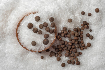 Black pepper and white natural salt as background, close up.