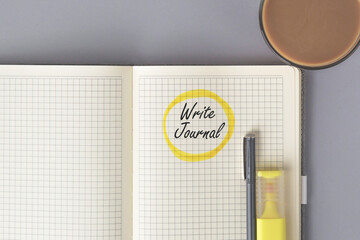 Open squared notebook with handwritten phrase write journal circled in yellow marker, pen,...