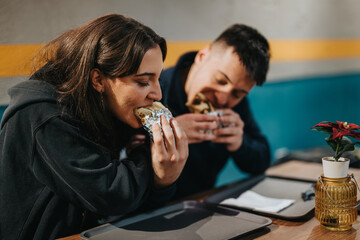 Two happy individuals savoring delicious wraps while dining at a cozy casual restaurant.