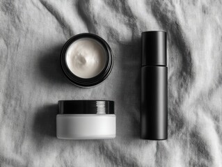 three cosmetic products with round cream jar and black cylinder bottle on grey cloth, minimalist style