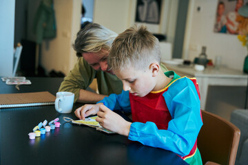 Mother and son painting together at home, developing creativity