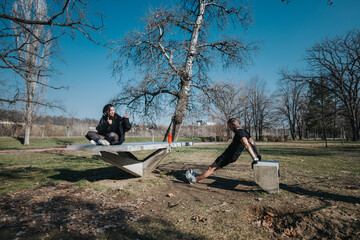 Two teenagers interact in an outdoor park for fitness activities during a bright day, showcasing...