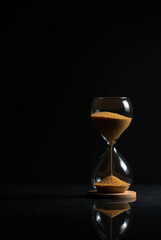 Classic Hourglass Mid-Drip with Flowing Sand on Black Background