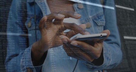 Tapping developer hands in denim jacket on phone touchscreen at tech workspace, with code overlay