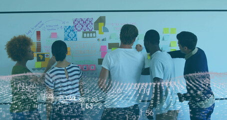 Collaborating five colleagues using whiteboard with sticky notes, charts and data overlay in office