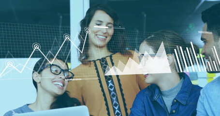 Analyzing office team collaborating on data charts at modern workspace, with laptop and graphs