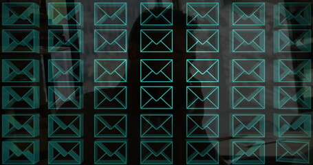 Displaying digital message grid projecting over dim office workspace, with turquoise envelope icons