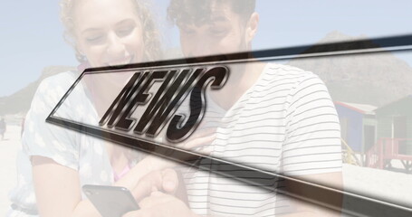 Smiling couple sharing smartphone on sand, with colorful wooden beach huts and NEWS graphic overlay