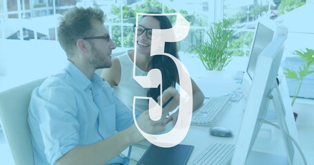 Two colleagues discussing work at desk with number five image overlay