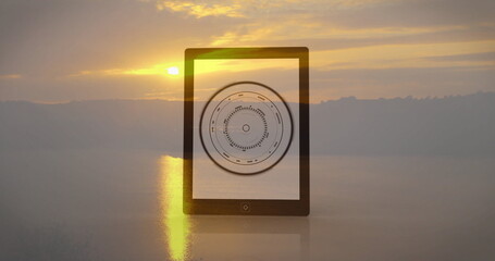Tablet showing circular data image against serene sunset landscape backdrop