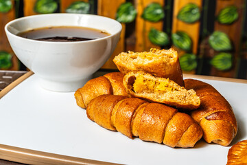 horizontal photo of breakfast with open empanada with pineapple inside and artisanal whole cheese sticks, sweetened with honey, next to a cup of coffee in a healthy vegetarian restaurant in Colombia