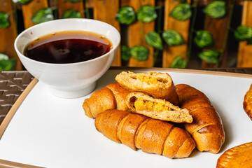 horizontal photo of breakfast with open empanada with pineapple inside and artisanal whole cheese sticks, sweetened with honey, next to a cup of coffee in a healthy vegetarian restaurant in Colombia