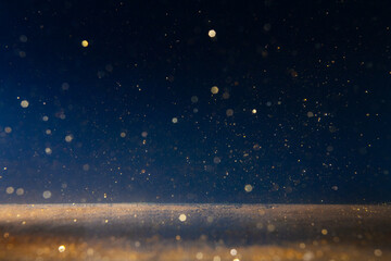 Sparkling golden particles drifting in the air against a dark background