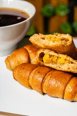 Vertical photo of breakfast with open empanada with pineapple inside and artisanal whole cheese sticks, sweetened with honey, next to a cup of coffee in a healthy vegetarian restaurant in Colombia