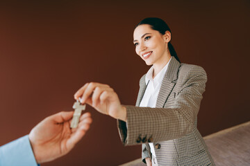 Young specialist businesswoman handing over house keys demonstrating success and professionalism in...