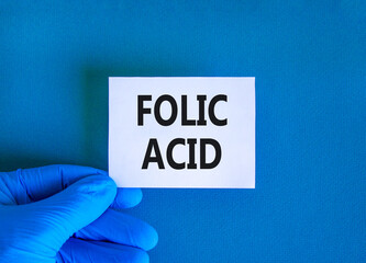 Folic acid symbol. Concept words Folic acid on beautiful white card. Doctor's hand in blue medical...